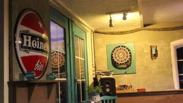 A room with a dartboard, a Heineken sign, and a speaker.
