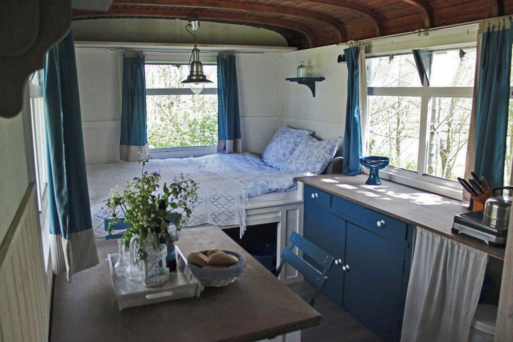 A cozy cabin interior with a bed, a dining table, and a kitchen area.