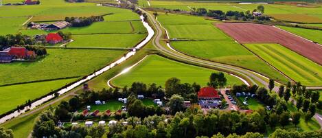 Vista aérea de una zona rural con campos, una carretera sinuosa y un conjunto de edificios con tejados rojos.