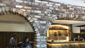 Un restaurante con un arco de ladrillo y una barra con salpicadero que imita el mármol.