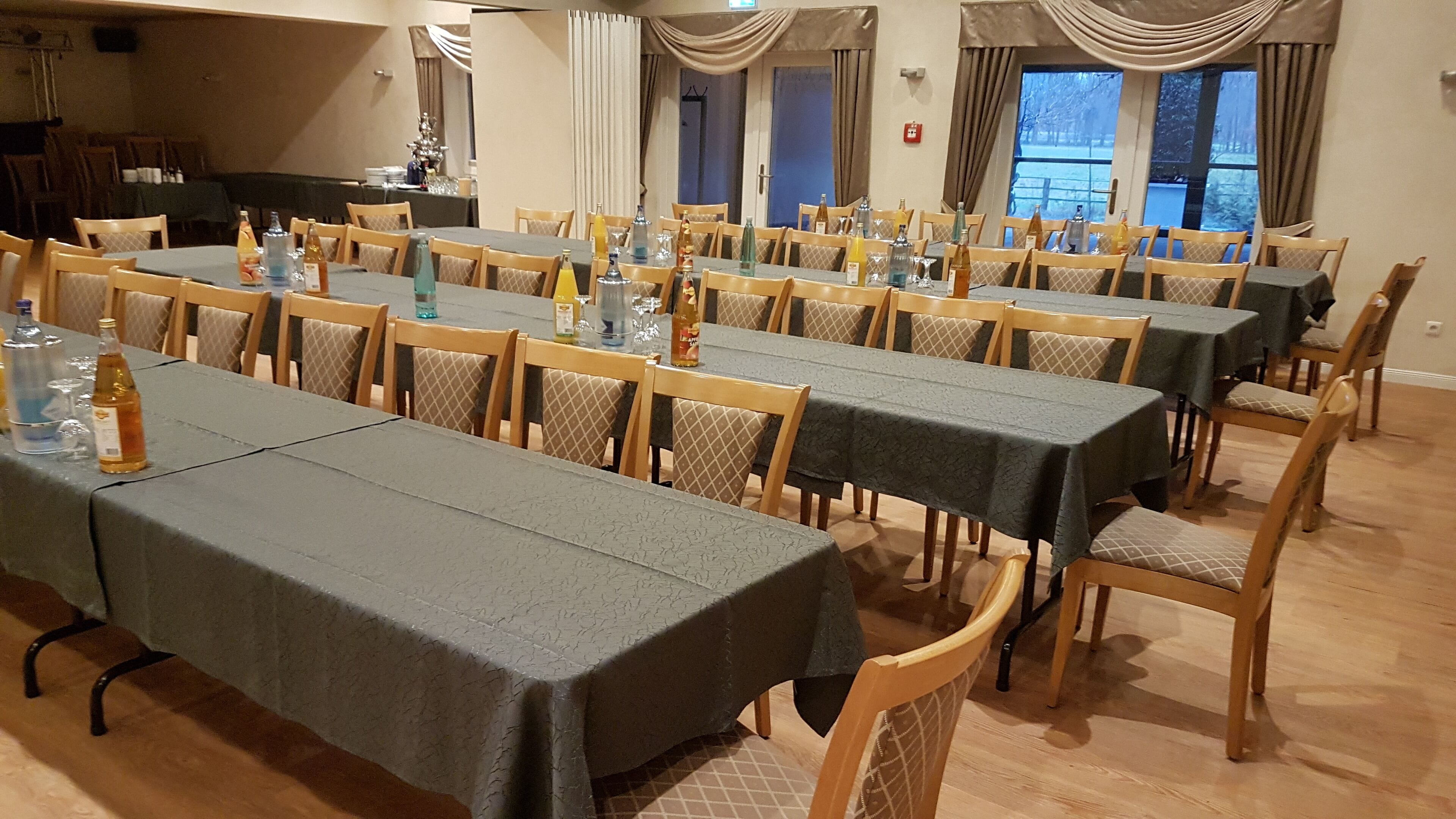 Ein großer Speisesaal mit mehreren Tischen und Stühlen, jeder Tisch mit einer grauen Tischdecke bedeckt.