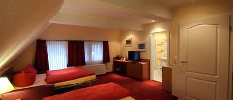 A hotel room with two beds, a television, a desk, and a door.