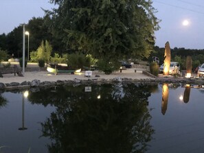 Un entorno tranquilo junto al lago, con barcos, un sendero de piedra y el reflejo de los árboles en el agua.