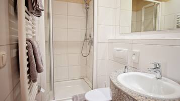 A modern bathroom with a glass-enclosed shower, a white toilet, and a granite countertop sink.
