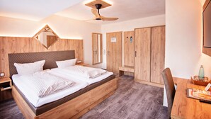 Un dormitorio moderno con cama de madera, ventilador de techo y armarios empotrados.