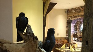 Un interior rústico con vigas de madera, una pared de piedra y una vitrina de madera con esculturas de aves.