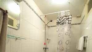 A small bathroom with a toilet, sink, and shower. - Residencial Funchal (Funchal)