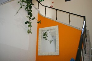 A staircase with an orange wall and a white-framed mirror. - Residencial Funchal (Funchal)