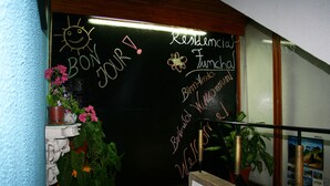 A blackboard with handwritten notes, a potted plant, and a staircase. - Residencial Funchal (Funchal)