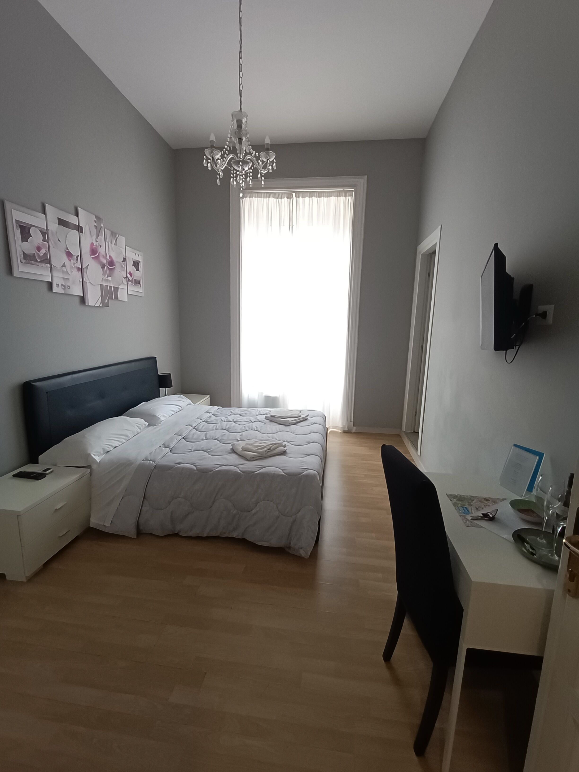 Une chambre à coucher comprenant un lit, une table de chevet, une télévision et un bureau avec une chaise.