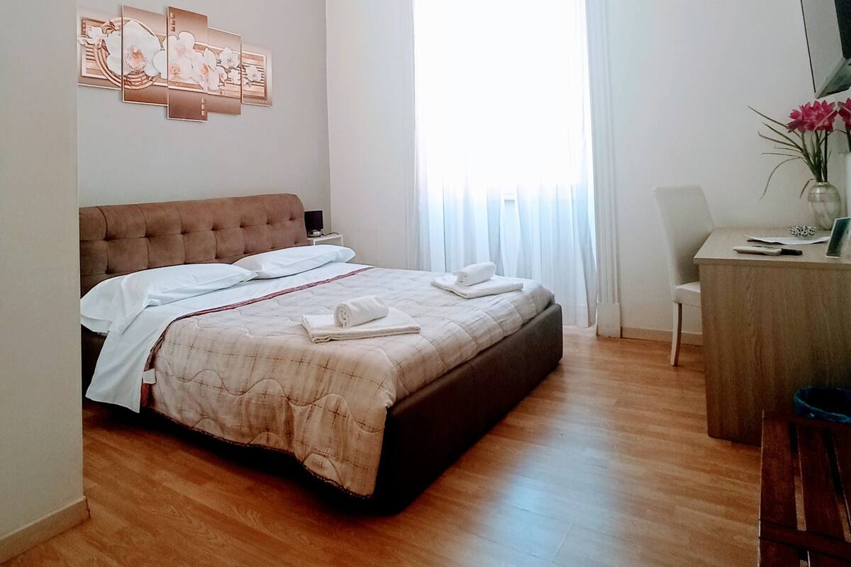 A bedroom with a large bed, a desk, and a chair.