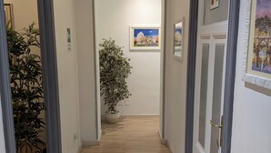 A hallway with wooden flooring, a potted plant, and framed artwork on the walls. - El Dorado Vatican (Rome)