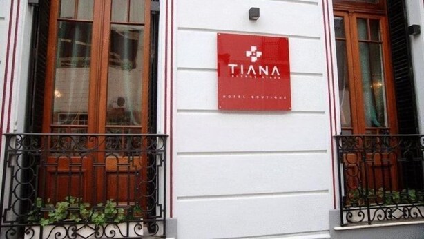 Fachada de hotel con un letrero rojo que dice "TIANA HOTEL BORDES" y una pared exterior blanca.