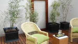 Una habitación con sillas de mimbre, una mesita pequeña y plantas en macetas.
