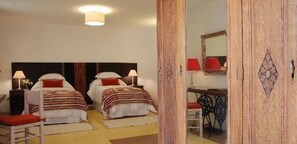 Une chambre d’hôtel avec deux lits, un bureau, une chaise et un miroir.