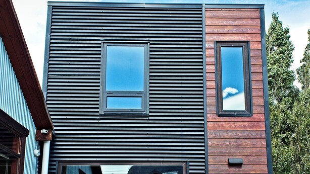 Ein modernes Gebäude mit einem großen Fenster und einer schwarzen Tür.