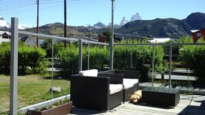 Eine Terrasse im Freien mit Korbmöbeln, einem Glastisch und einem schlafenden Hund.