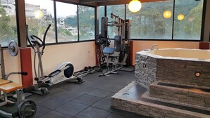 A gym with exercise equipment, a bench, and a stone-tub hot bath. - Chez Elena Guesthouse (Quito)