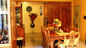 A dining room with a wooden table and chairs, a vase with flowers, and a wooden cabinet. - Chez Elena Guesthouse (Quito)