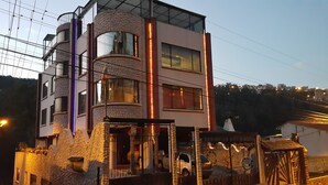 A multi-story building with a stone facade, large windows, and a balcony. - Chez Elena Guesthouse (Quito)