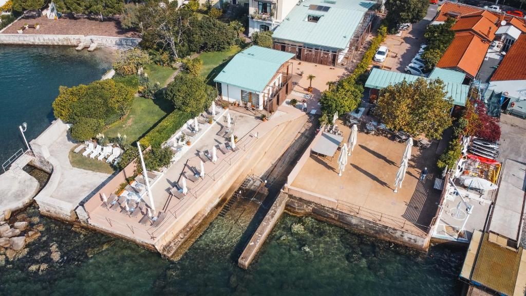 An aerial view of a waterfront property with a dock, a pool area, and adjacent buildings.