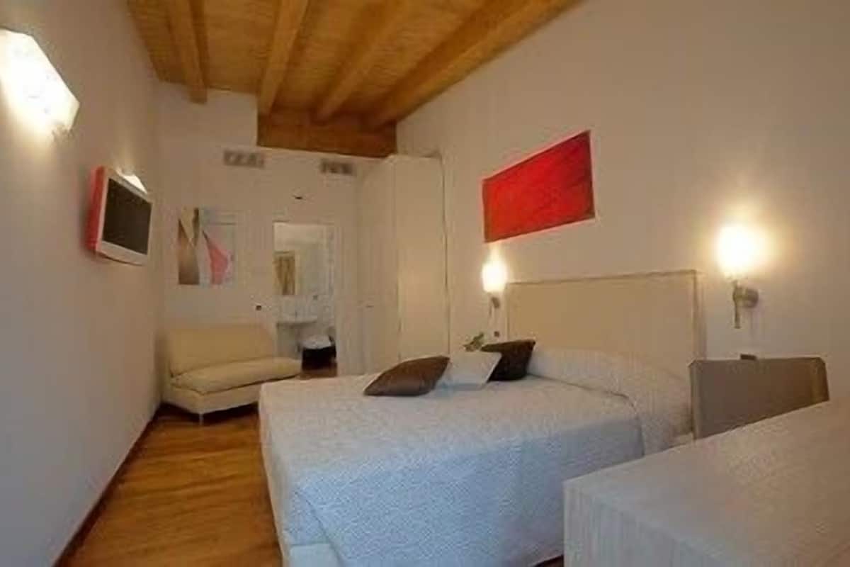 A bedroom with two beds, a chair, and a red wall decoration.