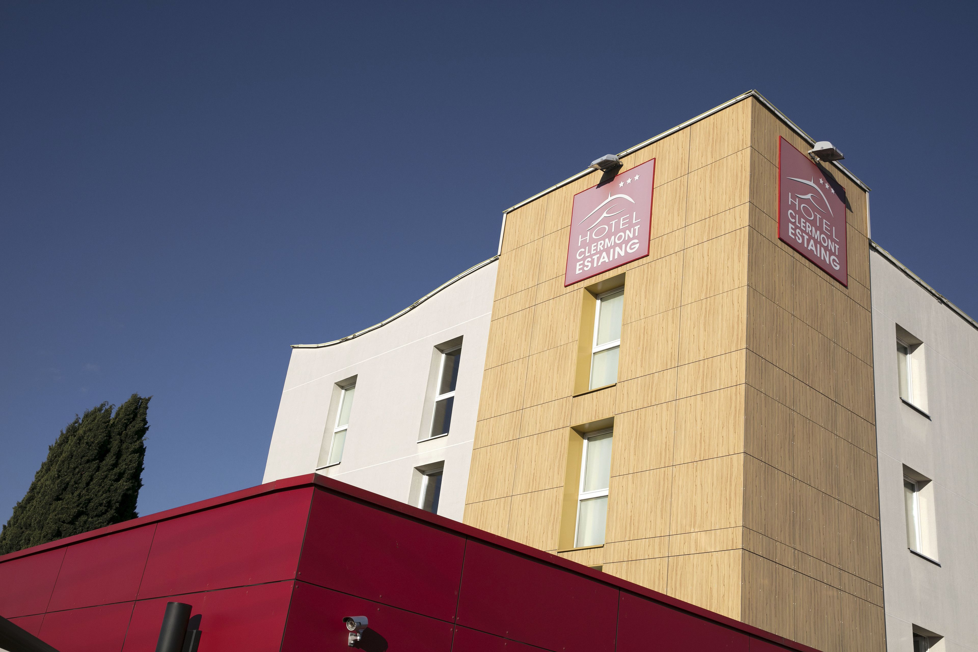 Un hôtel moderne avec une façade en bois et un toit rouge.