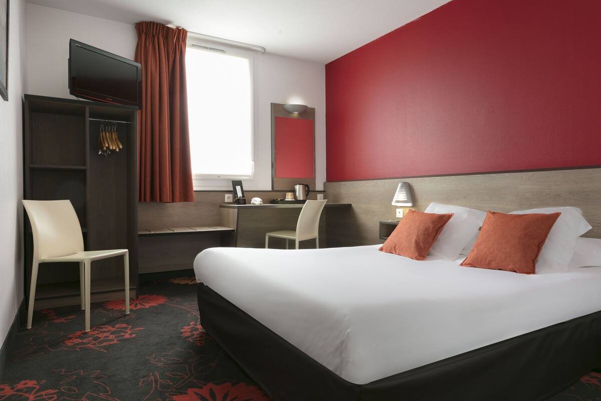 Une chambre d’hôtel équipée d’un lit, d’un bureau, d’une chaise et d’un téléviseur.
