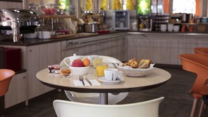 Una mesa de desayuno con un bol de fruta, un vaso de jugo de naranja, una taza y pasteles.