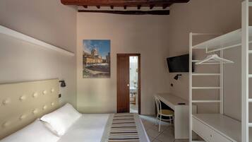 A hotel room with a bed, a desk, a chair, a TV, and a wardrobe.