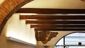 Un soffitto a volta in mattoni con travi in legno e un pannello decorativo intagliato.