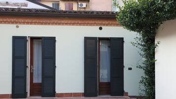 A building with two doors, each with a wooden door and black shutters, and a brick base.