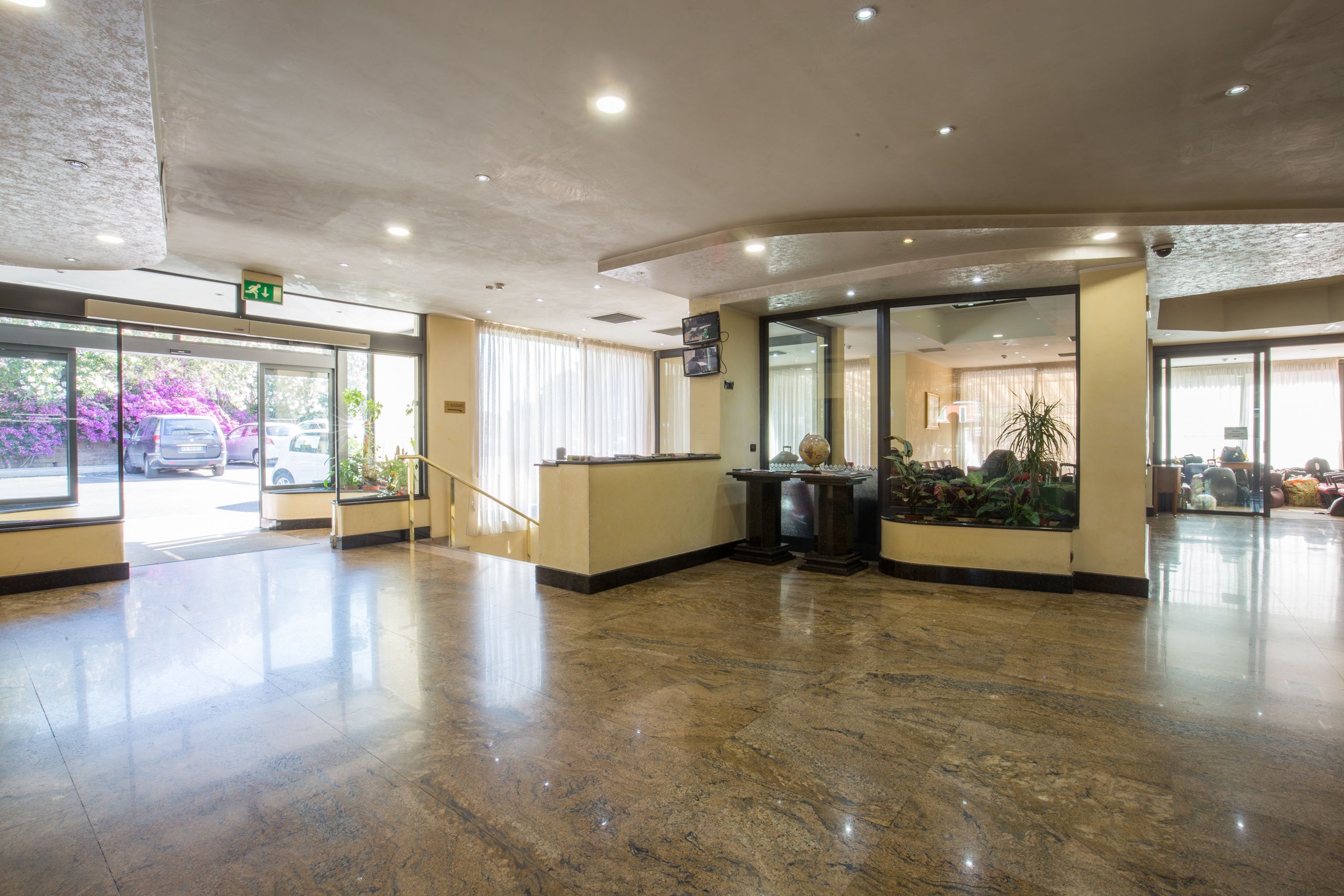 A spacious lobby with a marble floor, a reception desk, and a glass door leading outside.