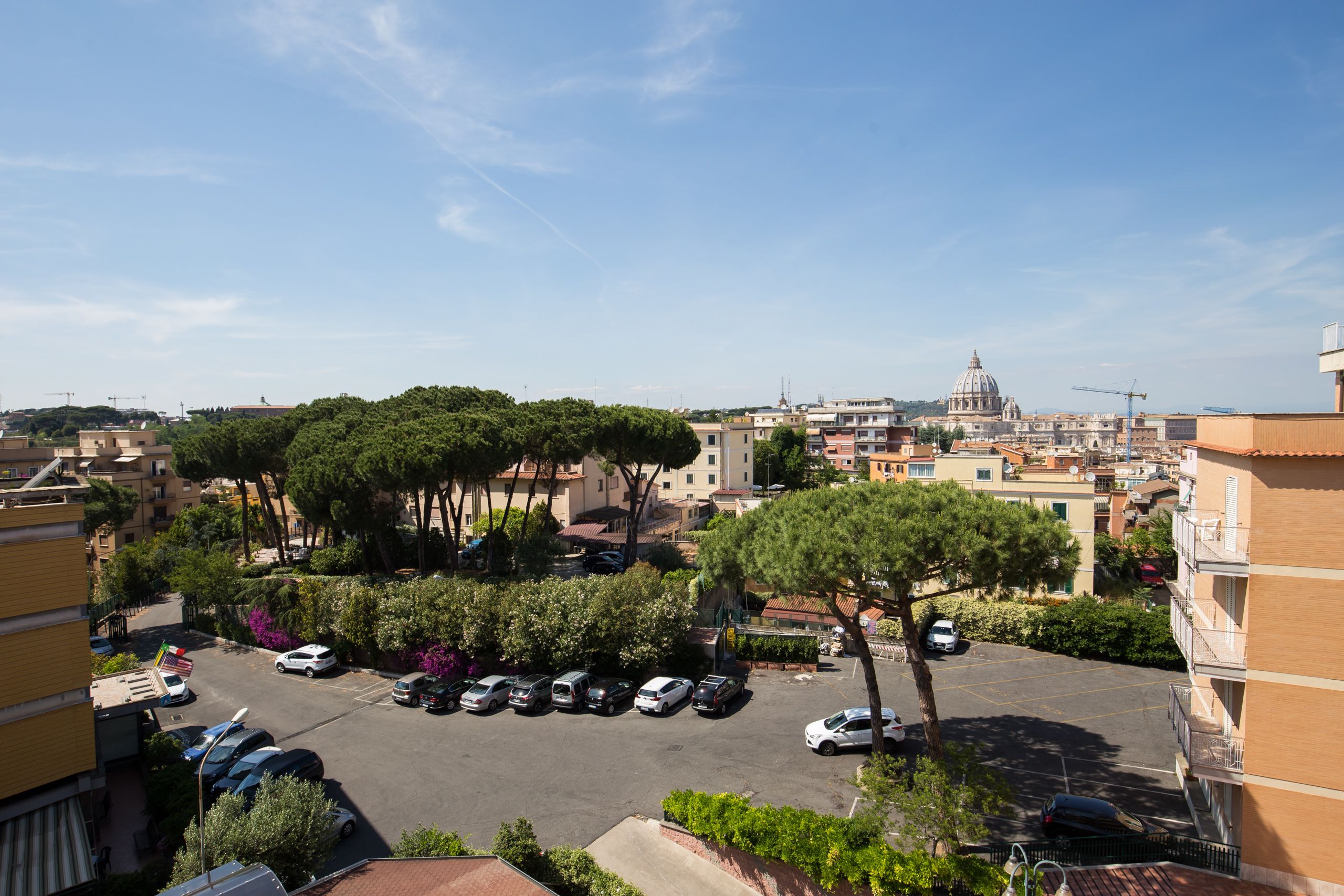 A parking lot with several cars, surrounded by trees and buildings.