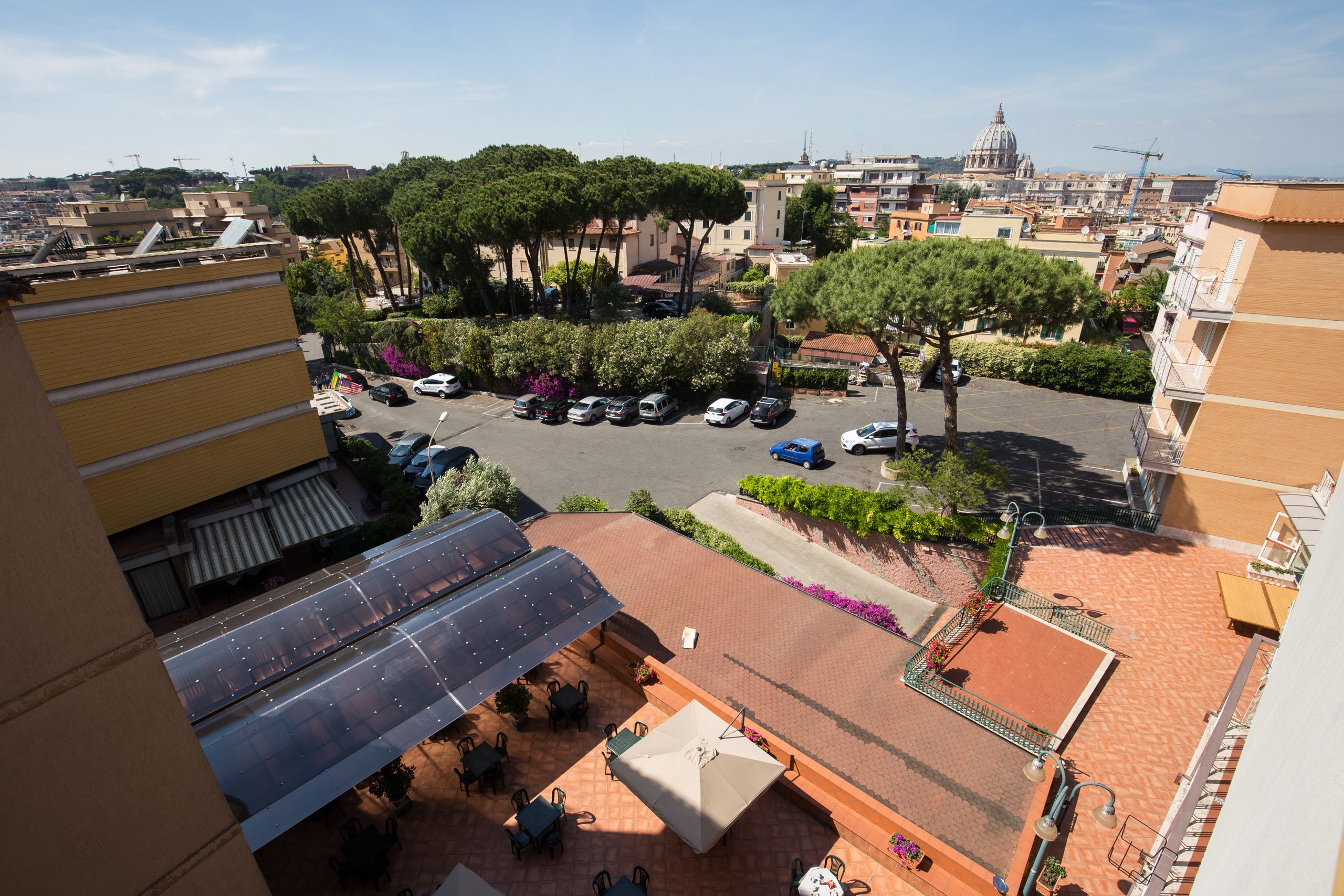 A rooftop terrace with outdoor seating, a parking area, and a view of the cityscape including a dome structure.