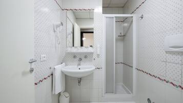 Un baño con lavamanos blanco, un espejo, ducha y retrete.