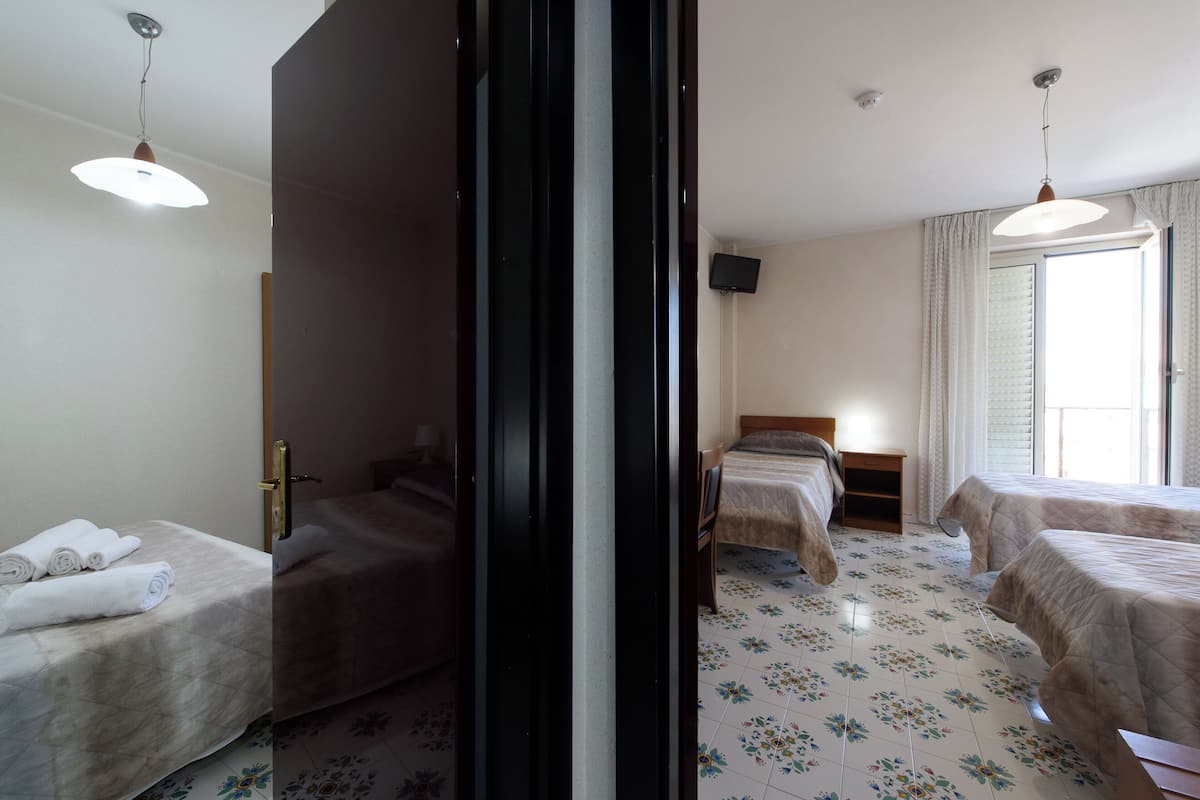 Una habitación de hotel con dos camas, televisión y ventana con cortinas.
