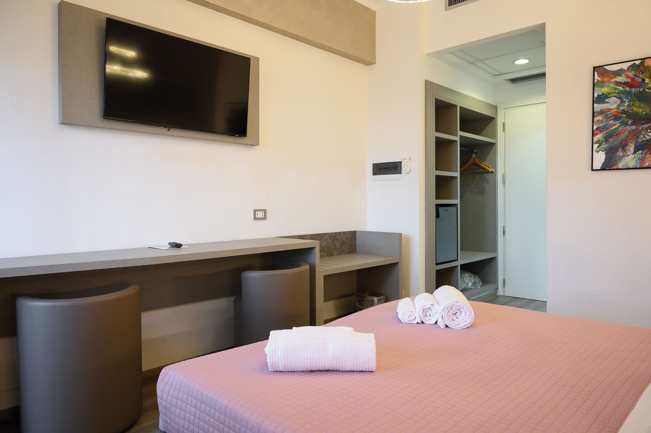 A hotel room with a bed, a TV, a desk, and a closet.