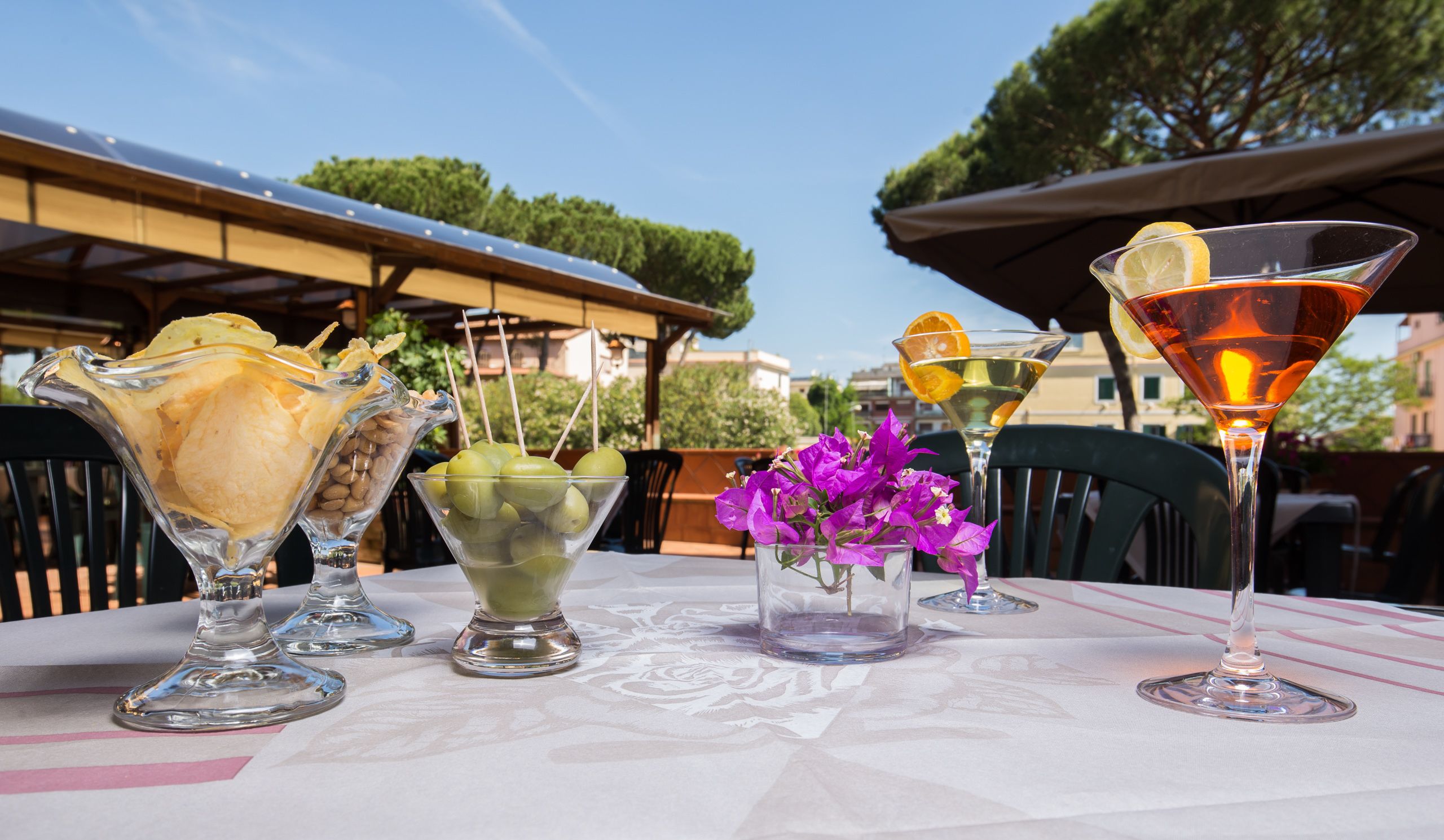 A table with various drinks and desserts, including a martini glass, a bowl of green apples, and a scoop of ice cream.