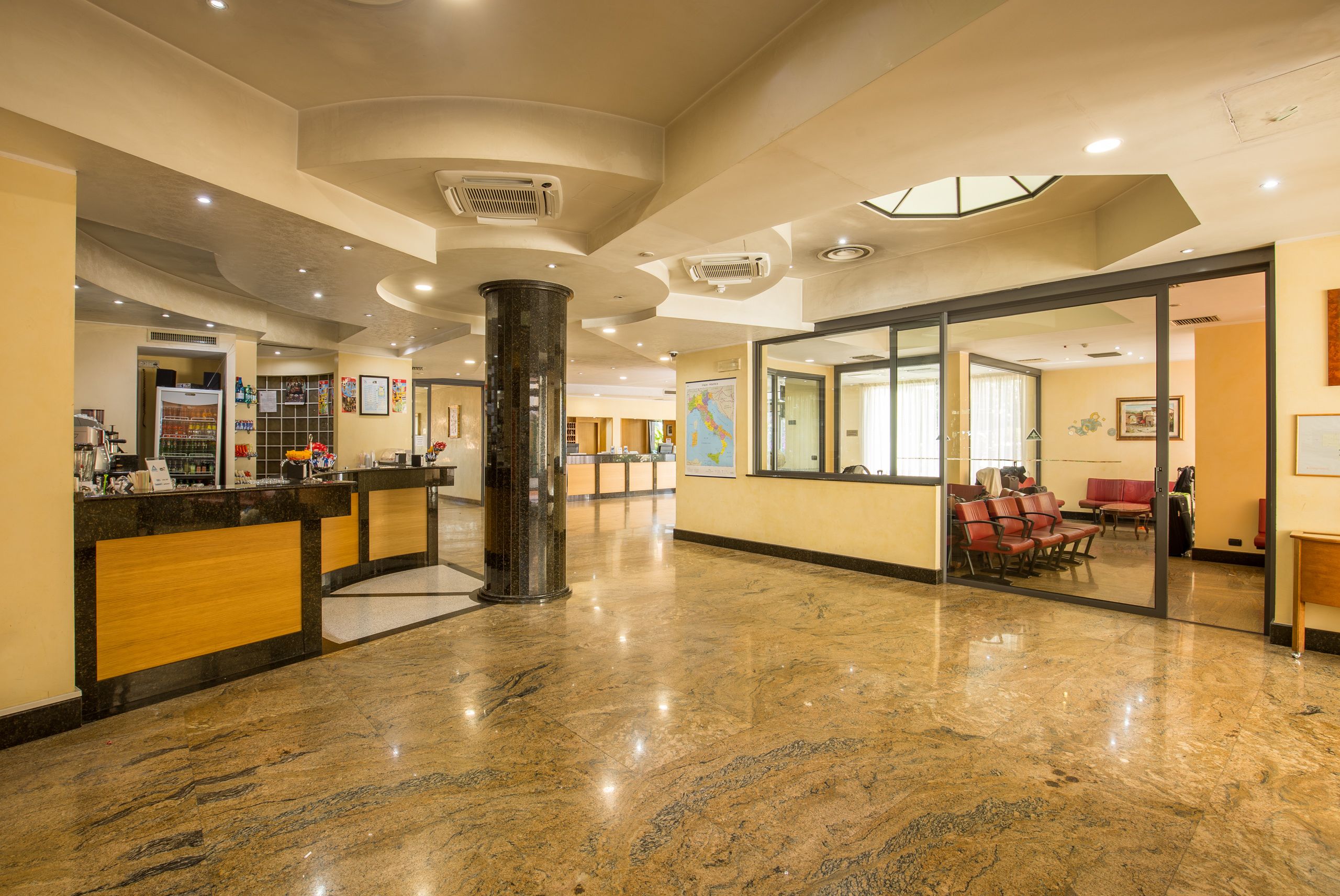 Un hall d’hôtel comprenant un comptoir d’accueil, un espace salon et une grande colonne.