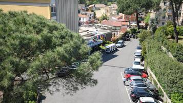 Parcheggio con auto e autobus, circondato da edifici e alberi.