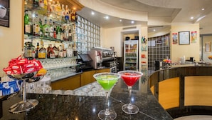 Een barruimte met diverse drankflessen en glazen, een koffiemachine en een toonbank met twee martini-glazen.
