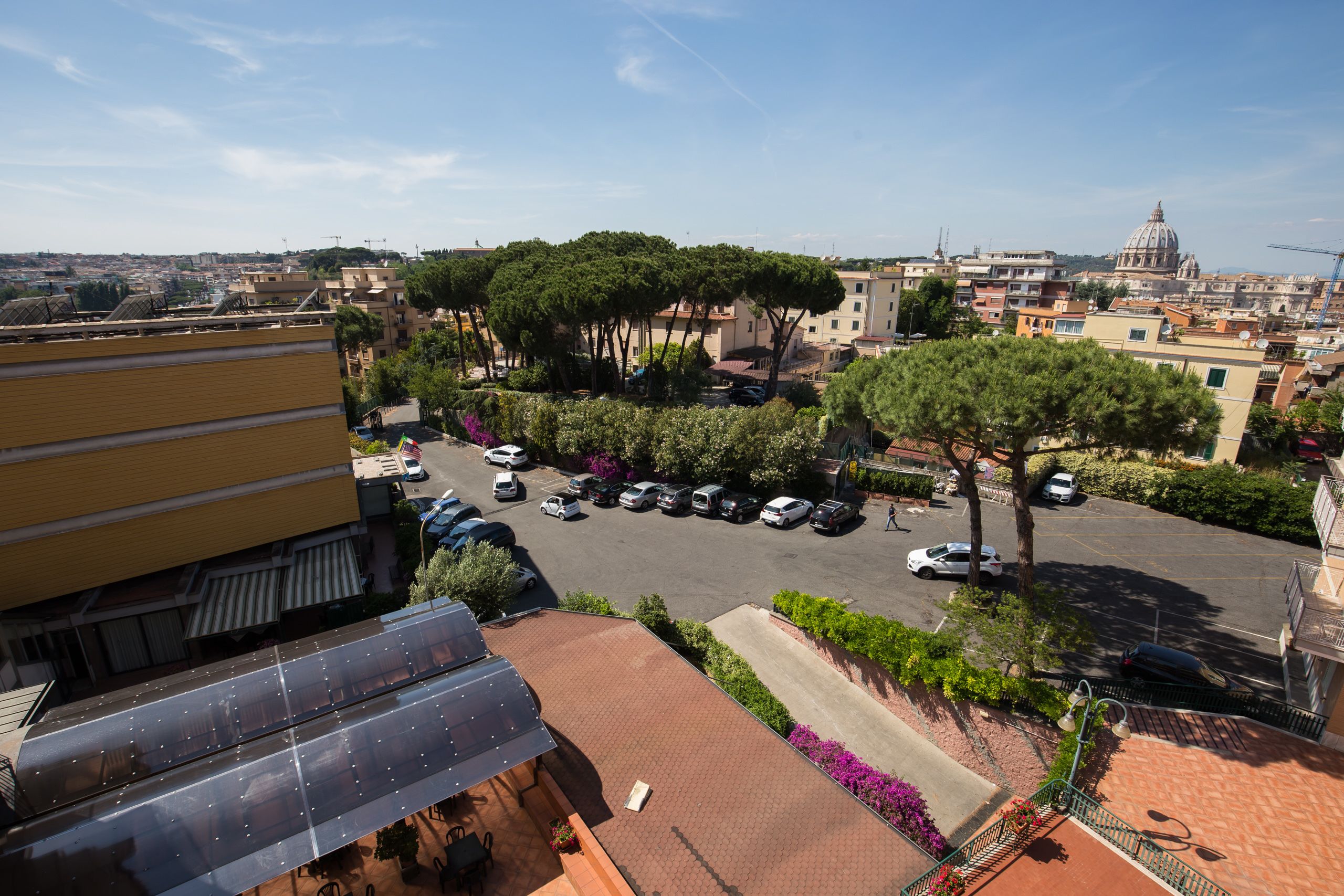 A parking lot with cars, a building with a yellow facade, and a dome structure in the background.
