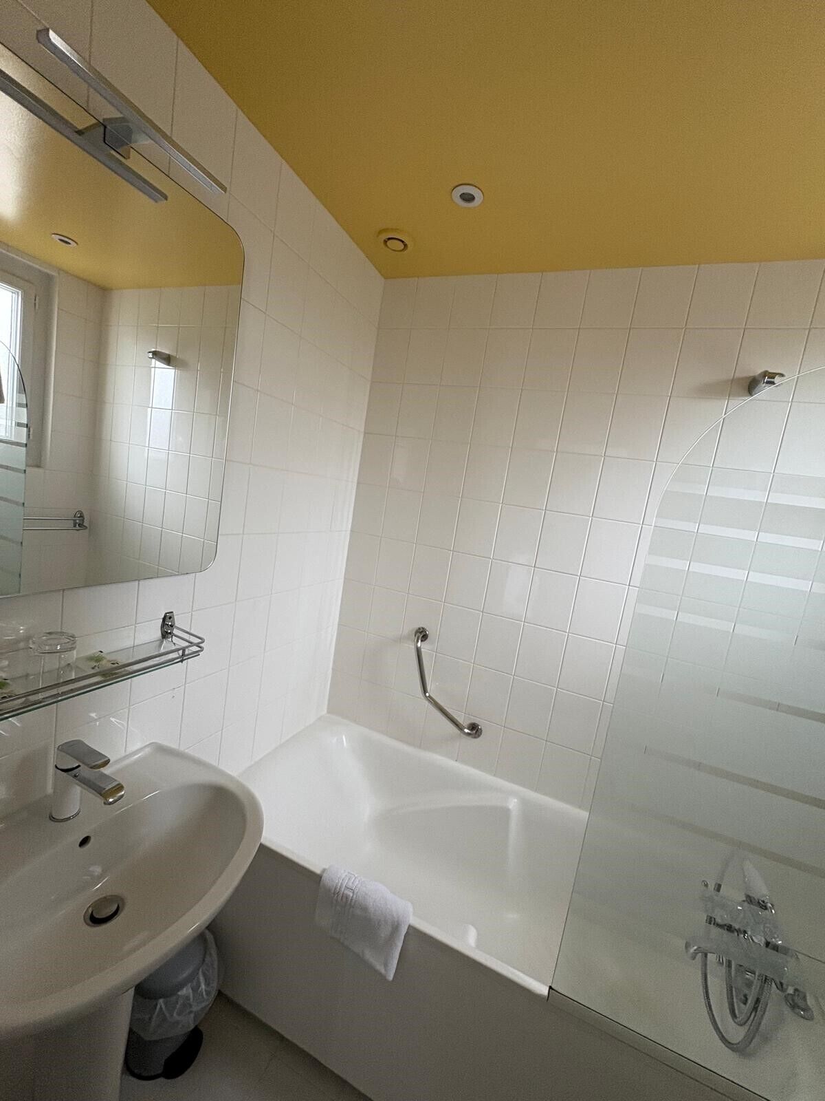 A bathroom with a white sink, mirror, and bathtub.