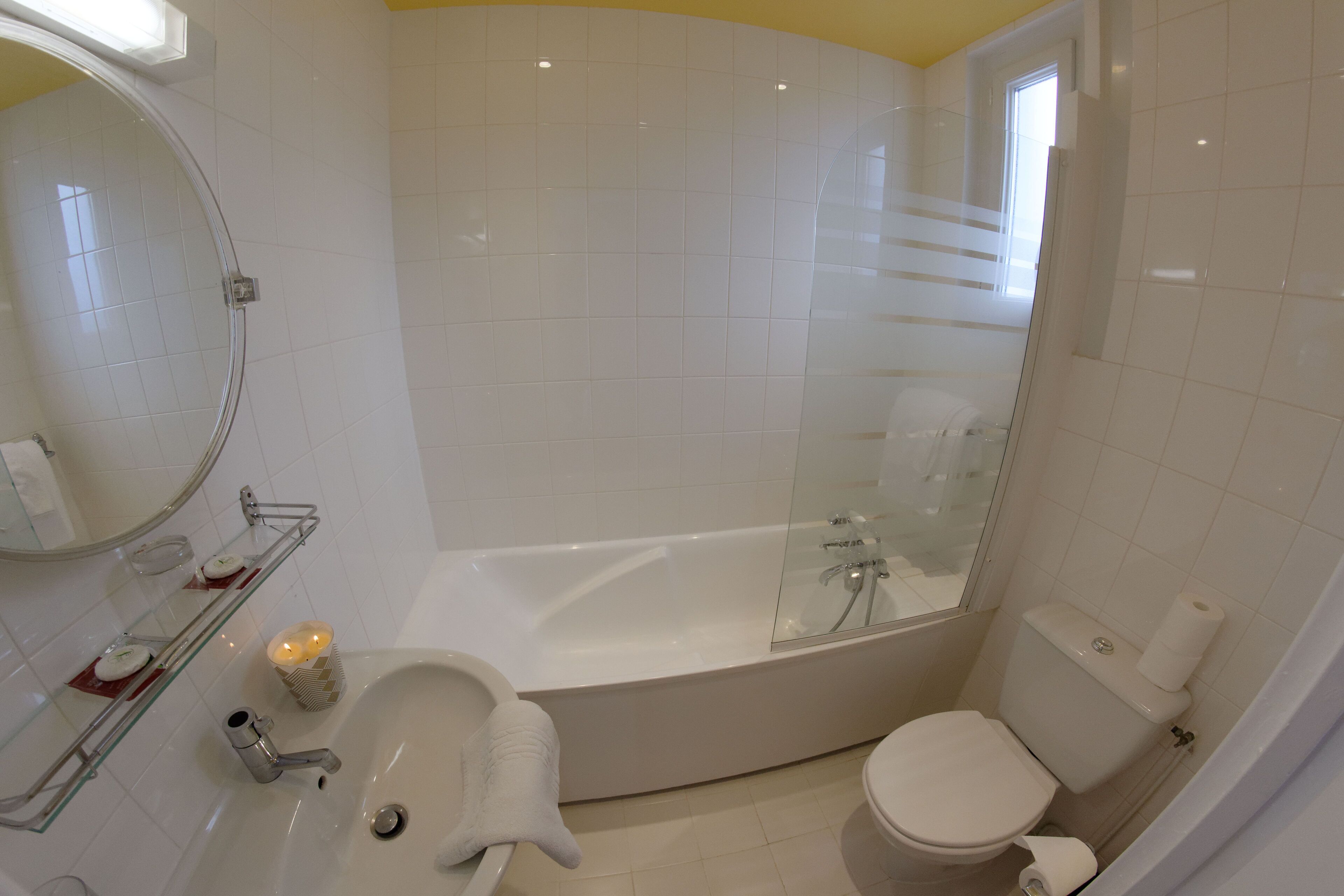 A bathroom with a bathtub, toilet, sink, and a glass-enclosed shower.