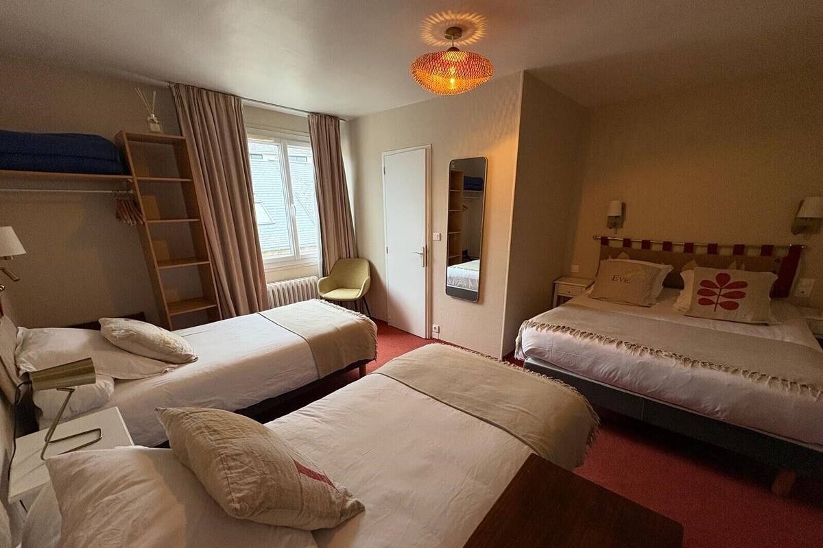 Una habitación de hotel con dos camas individuales, un escritorio, una silla, un armario y un espejo.