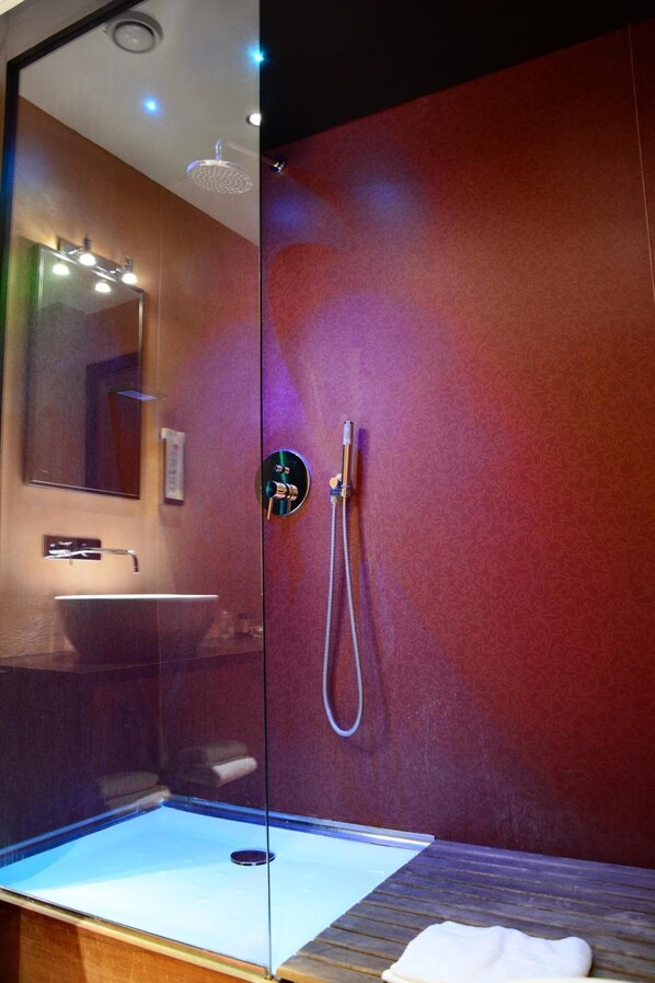 Un baño moderno con ducha de vidrio, lavamanos y espejo.