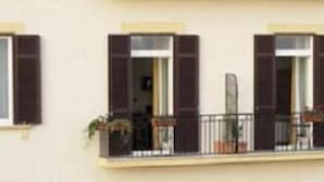 A building facade with three windows, each with dark shutters, and a balcony with potted plants. - Hotel Cimarosa (Naples)