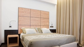 A modern hotel room with a large bed, a wooden headboard, bedside lamps, and a small wooden nightstand. - Hotel Cimarosa (Naples)