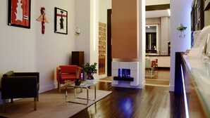 A modern hotel lobby with a wooden floor, a red sofa, a black armchair, a coffee table, and a fireplace. - Hotel Cimarosa (Naples)
